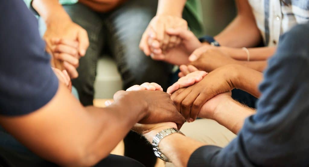 A group of people from different backgrounds joining hands together